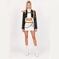 Adult model wearing the Rumi costume: black sequin jacket, gold shoulder armour, white crop top and shorts with belt and waist chains