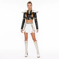 Adult model wearing the Zoey costume: black sequin top with gold collar detail, studded epaulettes, white pleated skirt and layered gold chains